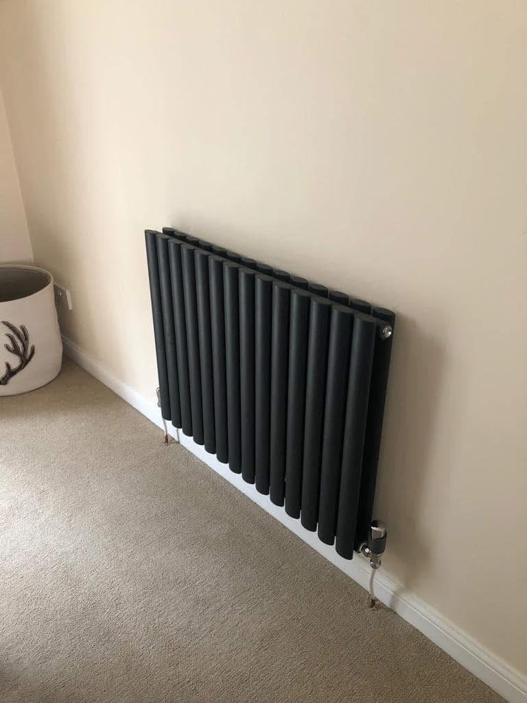 Anthracite column designer radiator fitted to a bedroom wall with chrome valves