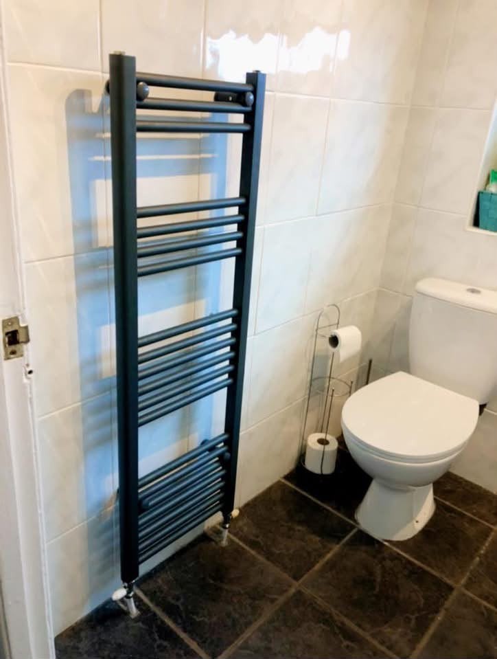 Anthracite heated towel radiator installed in a tiled bathroom