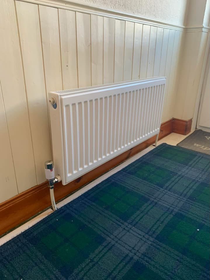 White single panel radiator installed in a hallway with timber panelling
