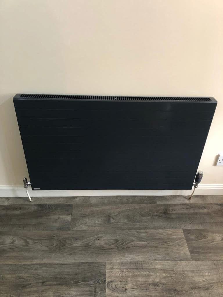 Anthracite flat panel radiator installed above a wood effect floor
