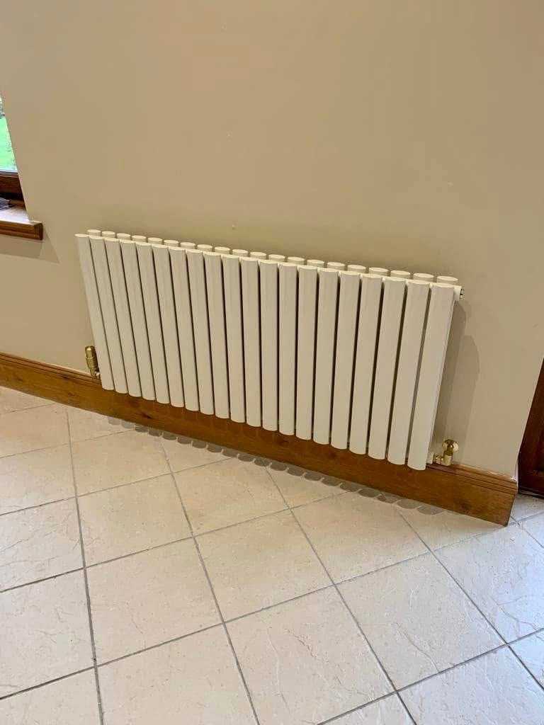 White horizontal designer radiator installed on a hallway wall above a tiled floor